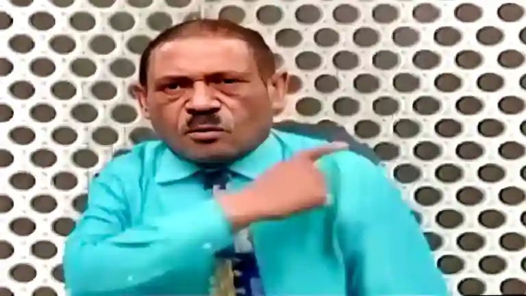 Man in bright sky-blue shirt pointing with a confident expression while making a sound