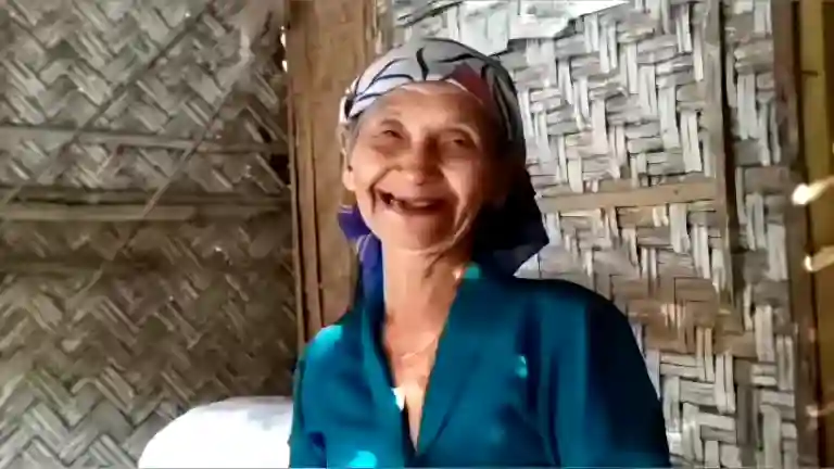 Elderly woman chuckling softly, her eyes crinkling with a warm smile in a home setting